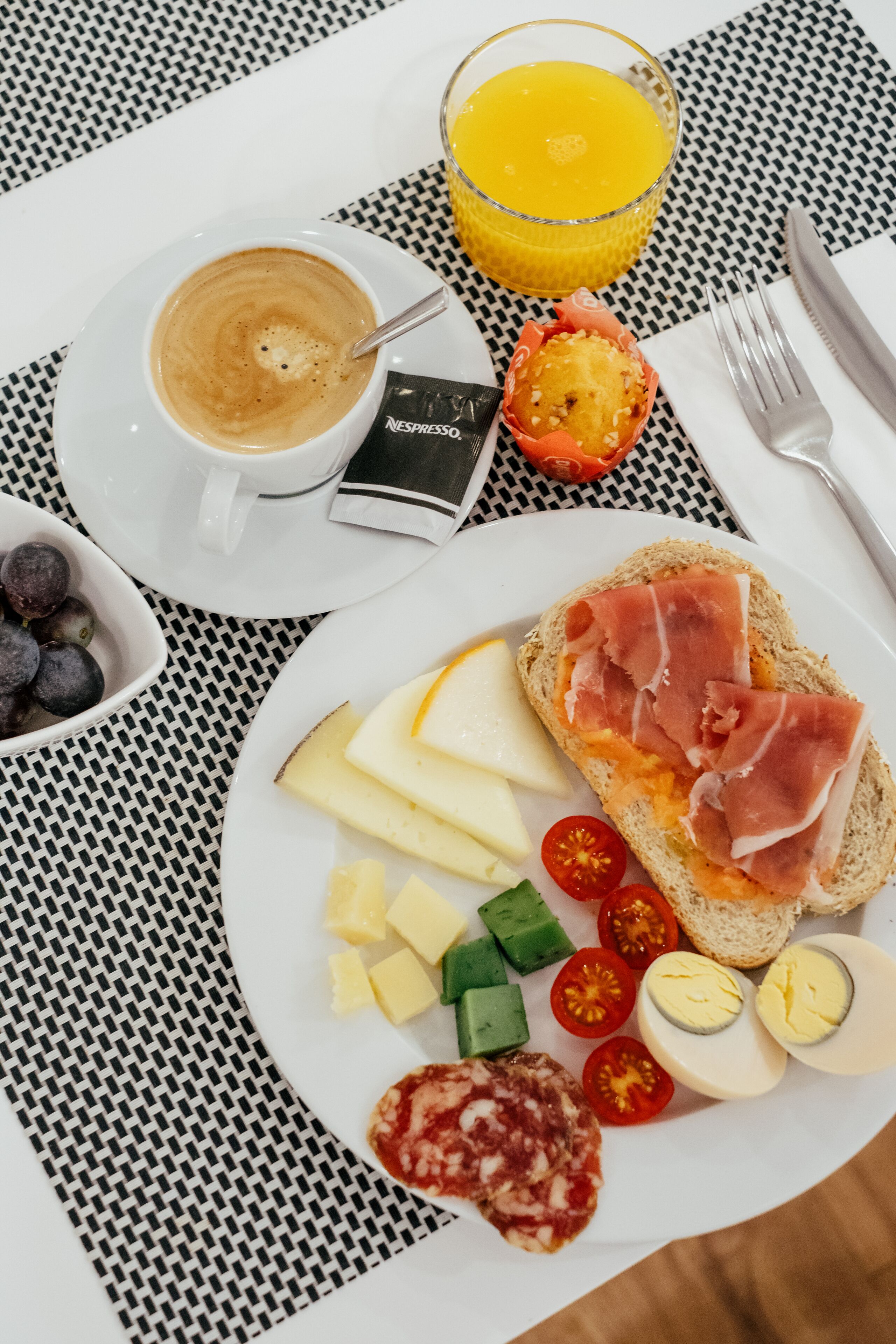 Ein Frühstückstisch mit einer Tasse Kaffee, einem Glas Orangensaft, Brot, Käse, Tomaten und Eiern.