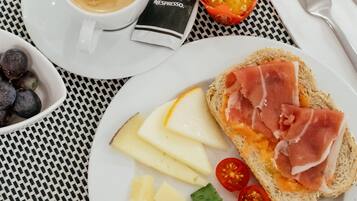 Ein Frühstückstisch mit einer Tasse Kaffee, einem Glas Orangensaft, Brot, Käse, Tomaten und Eiern.