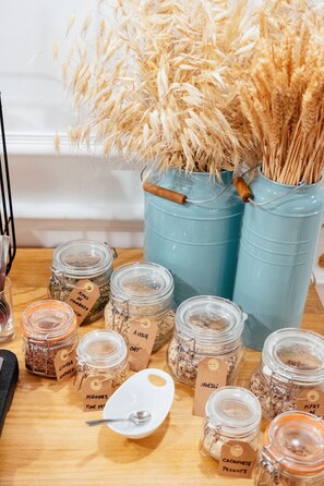 A wooden table with jars labeled with various food items and a white plate with a spoon. - Hotel Cetina Murcia (Murcia)