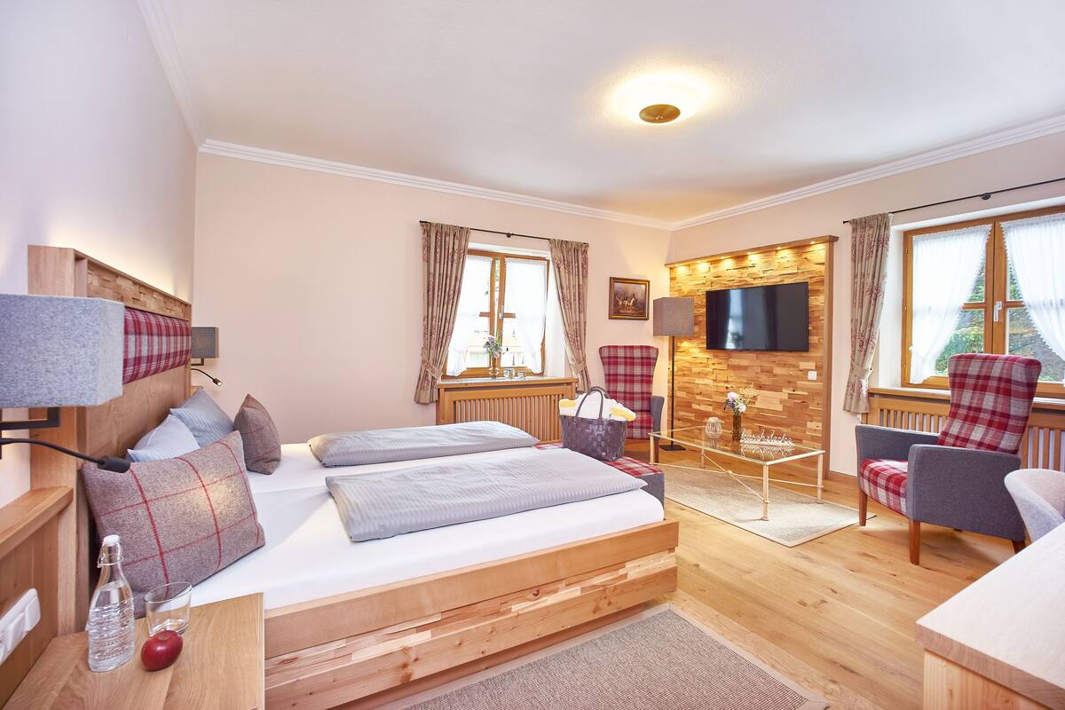 Ein gemütliches Schlafzimmer mit einem Holzbett, einem Fernseher und einem bequemen Sessel.