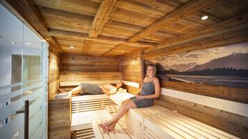 A wooden cabin with a sauna, wooden benches, and a mural of mountains.