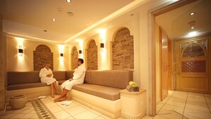 Un espace spa comprenant un coin salon, des murs décorés avec des pierres et un sol carrelé.