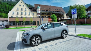 Un bâtiment moderne, avec un panneau indiquant un parking, une voiture et un paysage montagneux en arrière-plan.