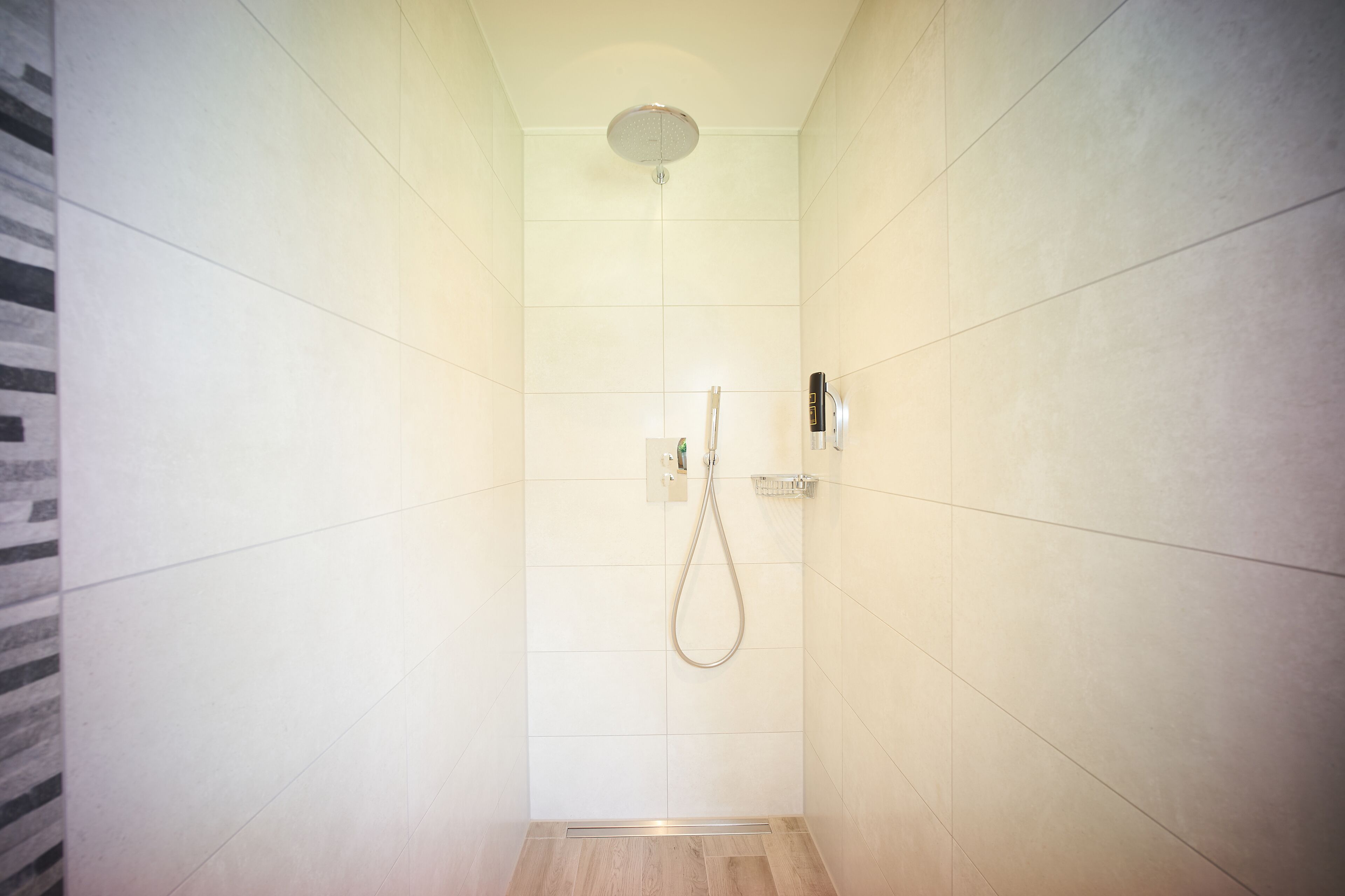A modern shower with a handheld showerhead and a wall-mounted control panel.
