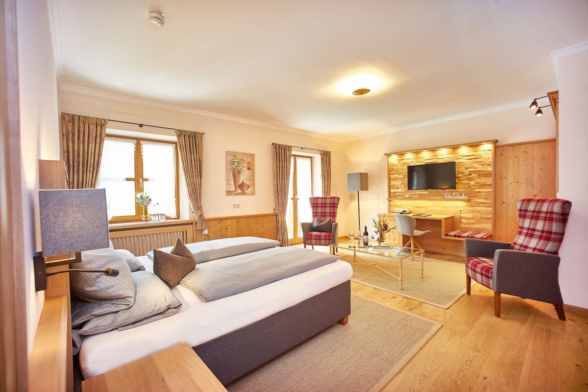 Ein Hotelzimmer mit einem Bett, zwei Sesseln, einem Fernseher und einer Holzwand.