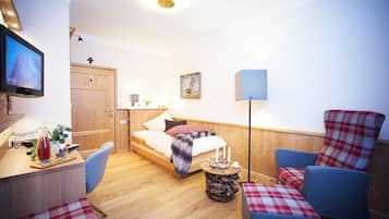 Ein gemütliches Zimmer mit einem Bett, einem Schreibtisch, einem Stuhl und einem kleinen Tisch mit einer Lampe.