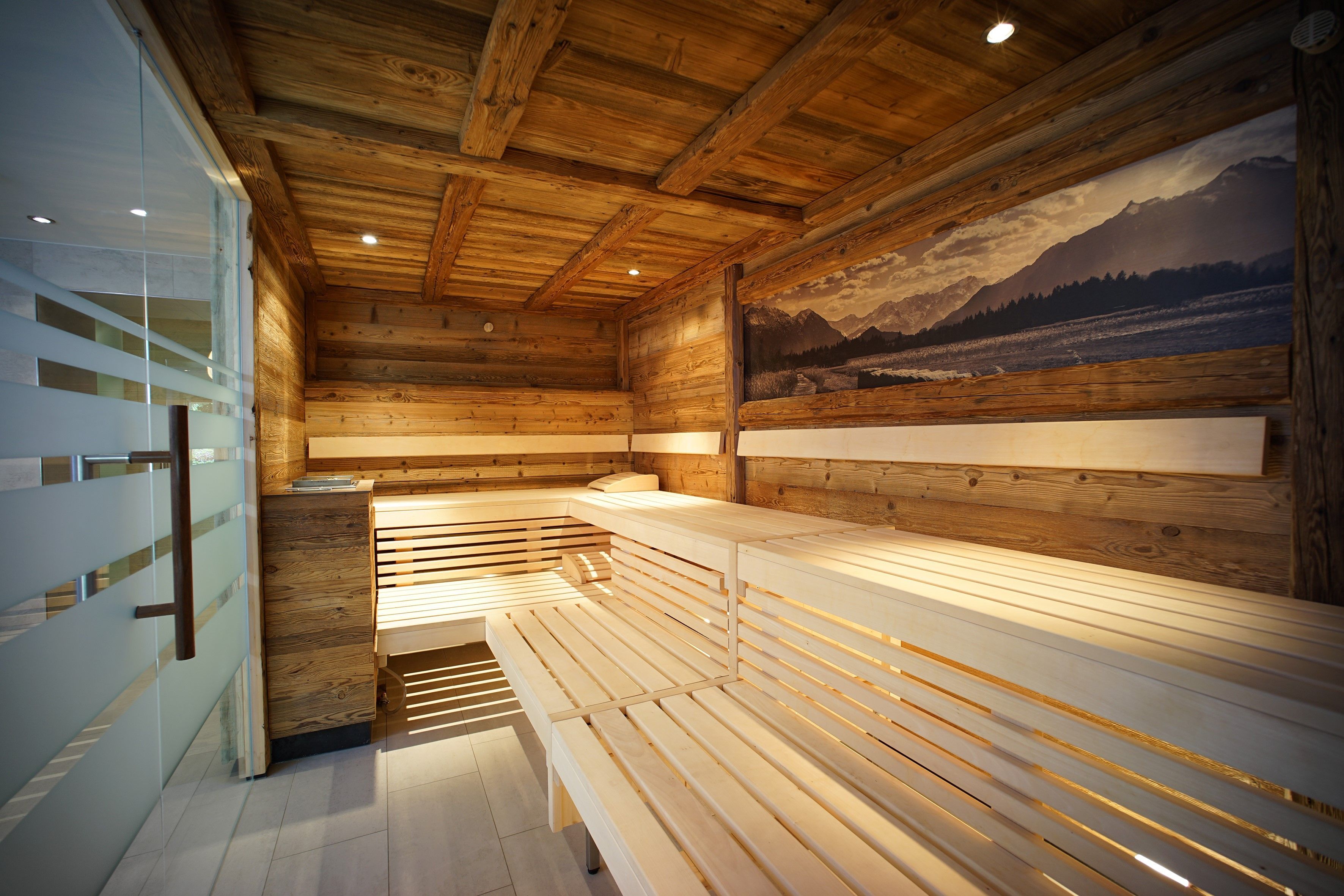 A wooden cabin interior with a bench, wooden walls, and a mountain view mural.