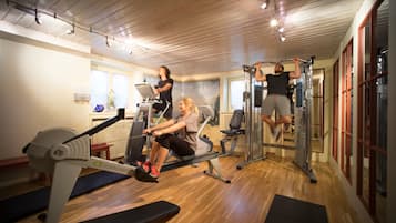 A gym with exercise equipment, wooden floors, and large windows.