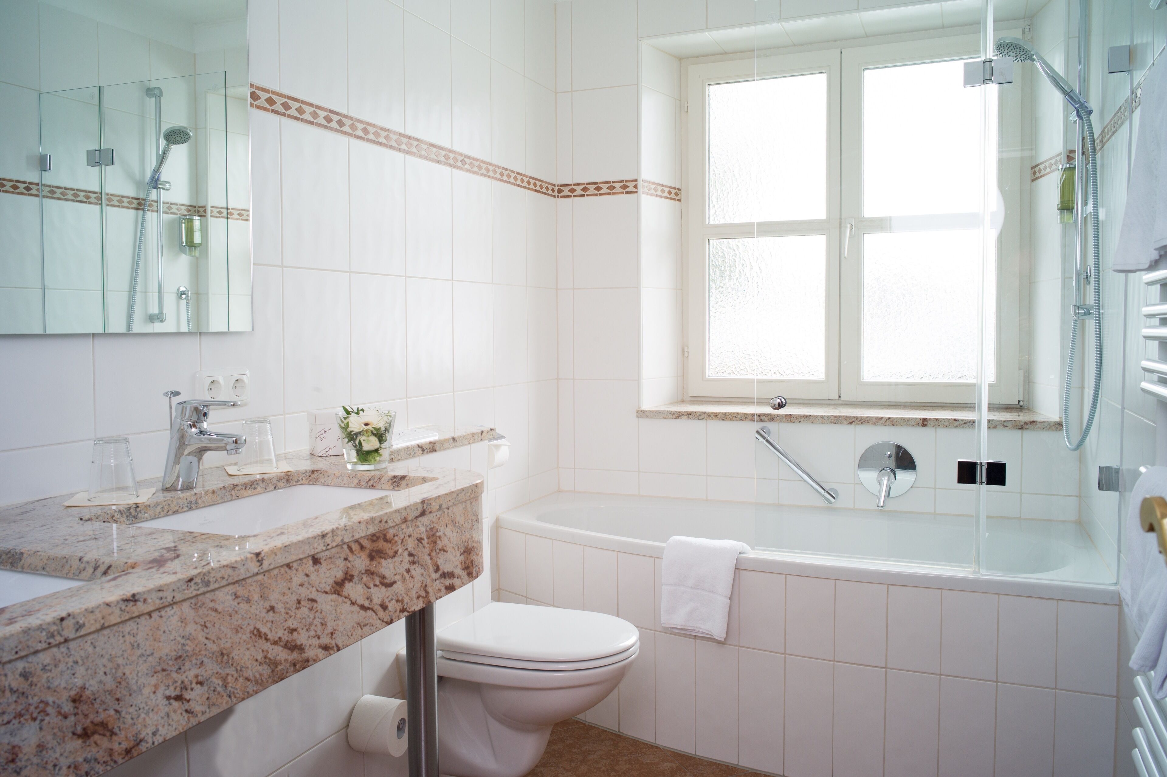 Un bagno con lavabo in marmo, WC, vasca e doccia.