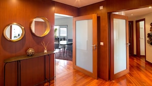 Un intérieur moderne avec un plancher en bois, une porte en verre et un miroir rond accroché au mur.