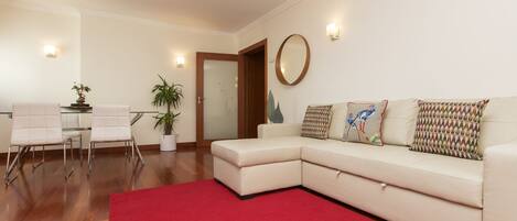 Una sala de estar moderna con un sofá modular, un tapete rojo y una mesa de centro de vidrio.