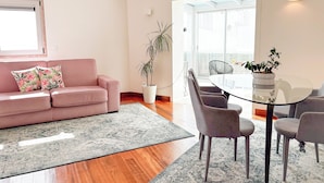 Un salon moderne avec un canapé rose, une table à manger en verre et une plante en pot.