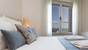 Une chambre d’hôtel avec un lit, des oreillers, une fenêtre donnant sur un beau paysage et une lampe.