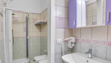 Ein Badezimmer mit Dusche, Toilette, Waschbecken und Spiegel.