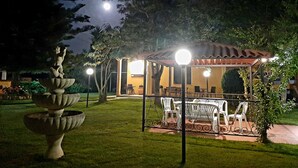 Un jardín con pérgola, mobiliario exterior y una fuente decorativa.