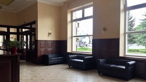 Un hall d’entrée spacieux, doté de grandes fenêtres, d’un comptoir de réception et d’une plante en pot.