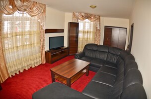 A living room with a black leather sofa, a wooden coffee table, and a television on a stand.