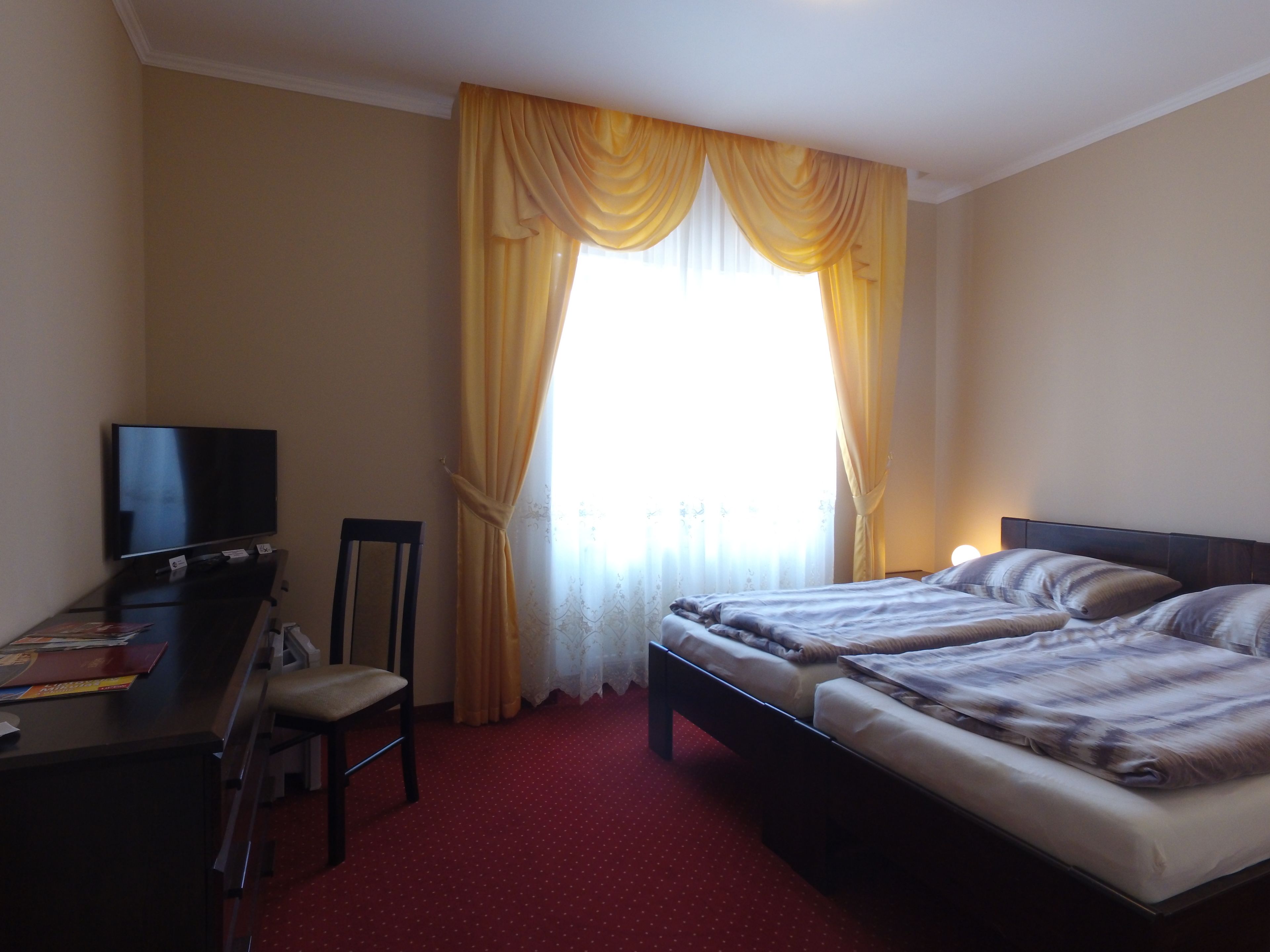 A hotel room with a bed, a desk, and a TV.