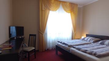 A hotel room with a bed, a desk, and a TV.