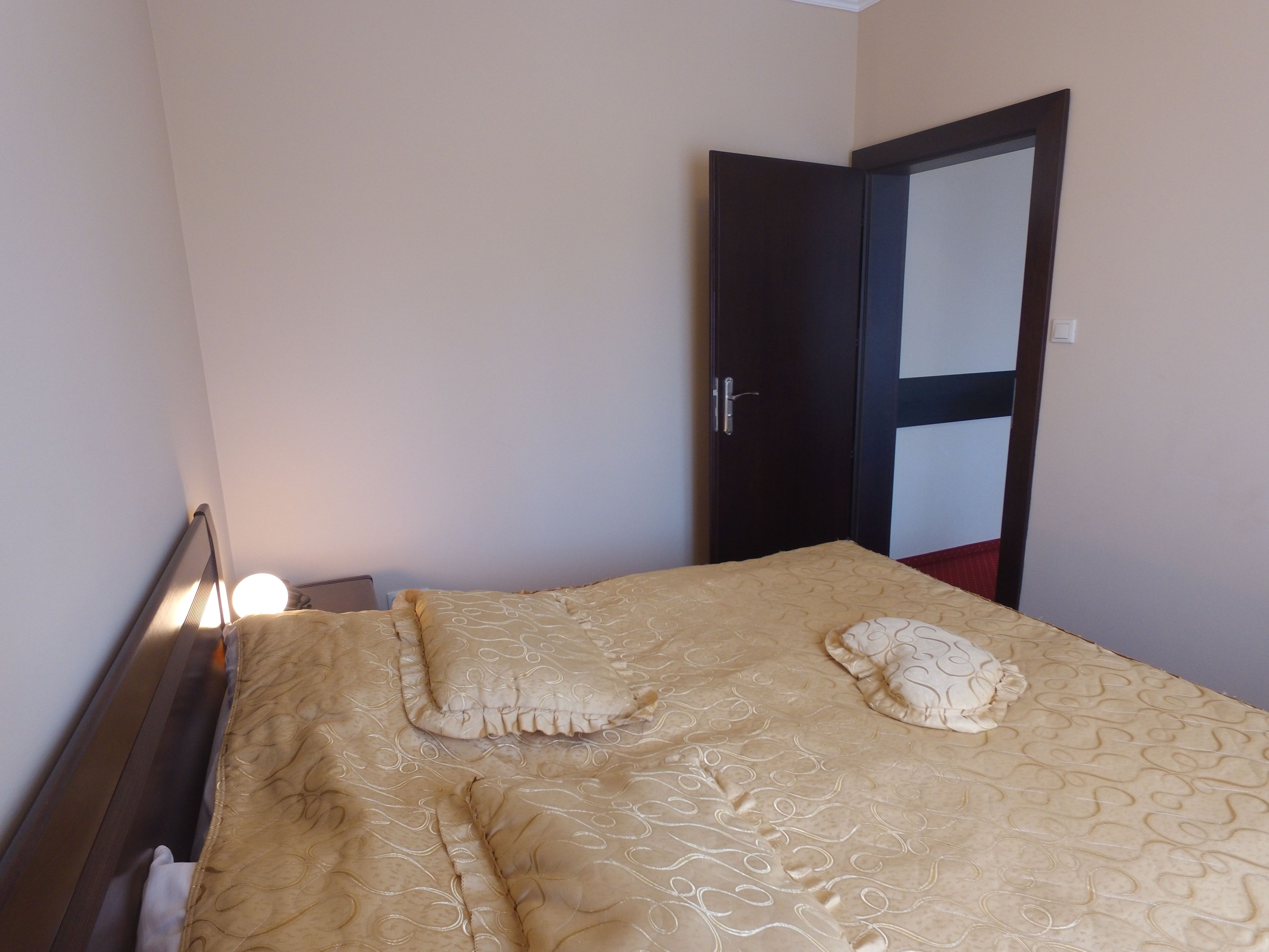 A bedroom with a bed, a nightstand, and a door.