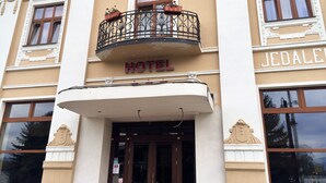 Un hôtel doté d’un balcon, d’une enseigne indiquant « HÔTEL » et d’une façade ornée d’éléments décoratifs.