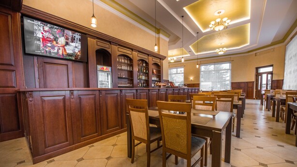 Un restaurant avec des boiseries, un bar et de nombreuses tables et chaises.