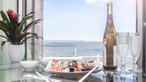 A table with sushi, a bottle of wine, and two glasses, overlooking a body of water with a bridge in the distance. - Oriente 57 Apartments by APT IIN - Parque das Nações (Lisbon)