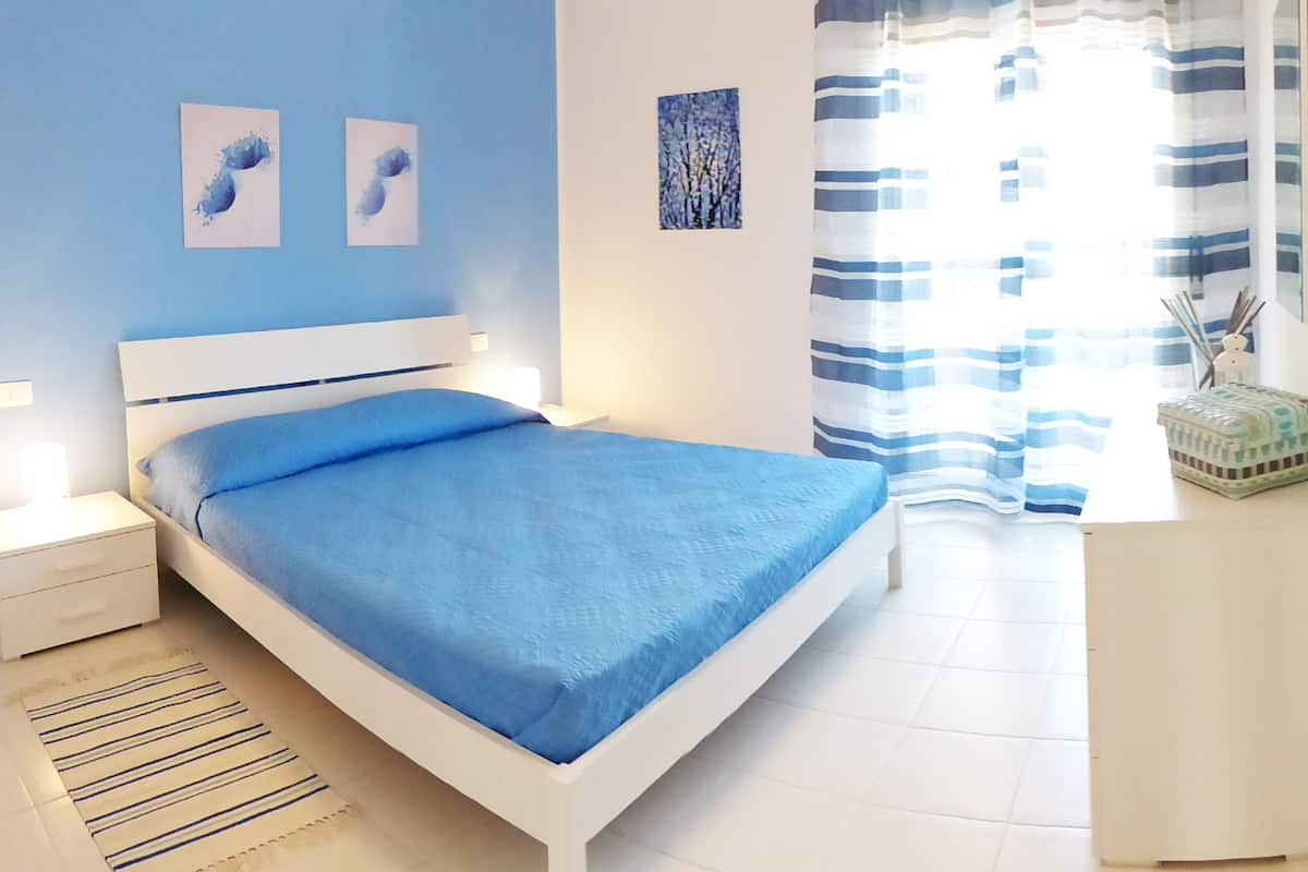 Un dormitorio con cama, mesita de noche y un pequeño armario.