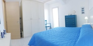 Ein Schlafzimmer mit Bett, Kleiderschrank, Stuhl und Schreibtisch.