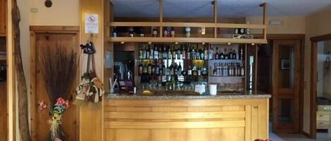A bar area with wooden shelves stocked with bottles, a counter, and a sign indicating no smoking.
