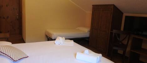 Een hotelkamer met een groot bed, een kleiner bed, een houten garderobe en een bureau met een stoel.