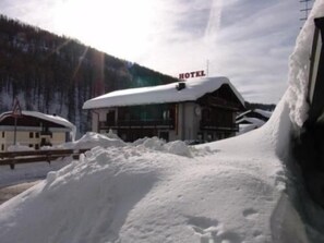 Un hôtel dont le toit est recouvert de neige et sur lequel on peut voir une enseigne indiquant son nom.