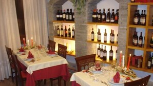 Comedor con mesas dispuestas para una comida, rodeado de botellas de vino en estanterías.