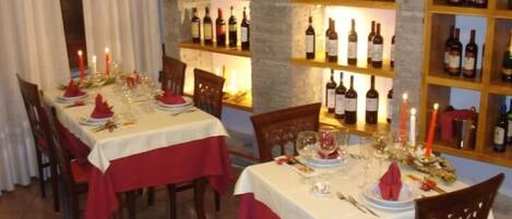 A dining area with tables set for a meal, surrounded by wine bottles on shelves.