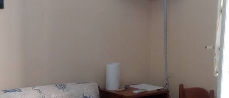 Una habitación con una televisión montada en la pared, un sofá, una mesa con una caja verde y una silla.