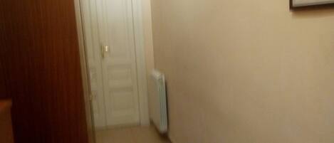 A hallway with a wooden door, a radiator, and a framed picture on the wall.