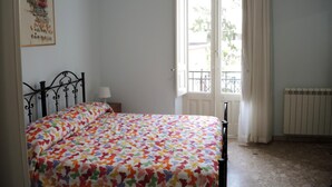 A bedroom with a bed, a window with a view, a radiator, and a wall with a framed picture. - La Casa di Ermelinda (Reggio Calabria)