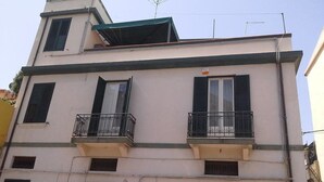 A multi-story building with balconies, a flat roof, and a visible antenna. - La Casa di Ermelinda (Reggio Calabria)