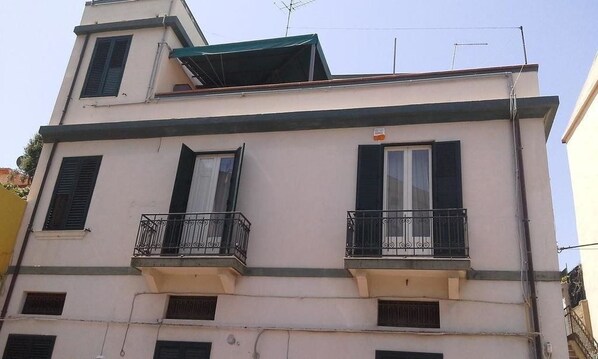 Stylish building with a flat roof and second-floor balcony, offering a view of the surrounding area.