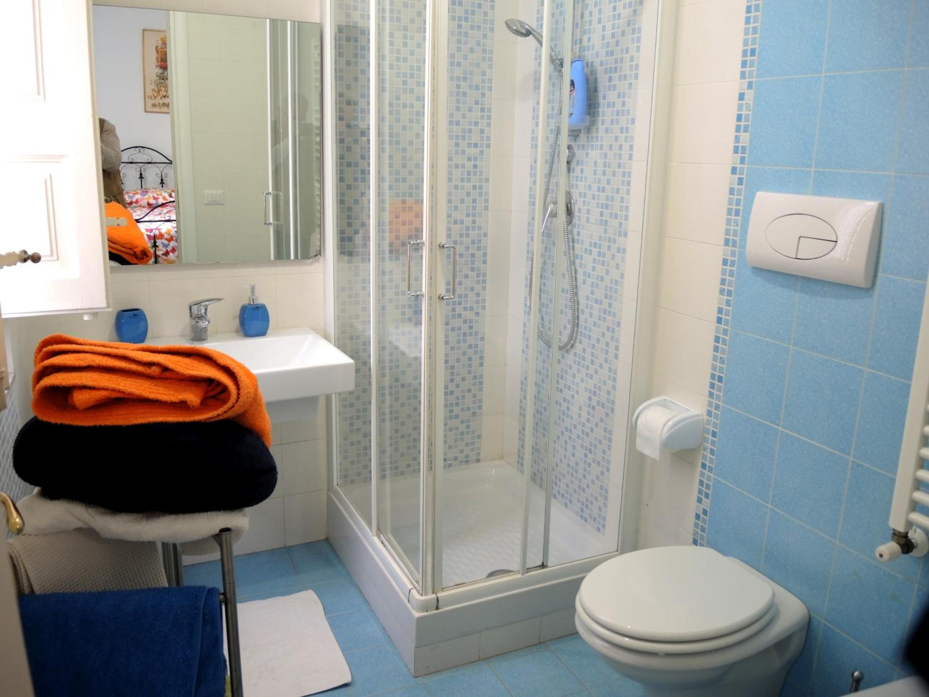 Un baño con ducha de vidrio, lavamanos blanco y un inodoro.