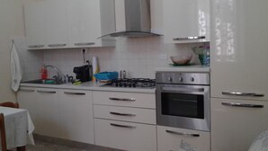A kitchen with white cabinets, a gas stove, an oven, and a sink. - La Casa di Ermelinda (Reggio Calabria)
