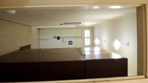 A room with a large wooden bed, a white door with a window, and a light fixture on the wall. - La Casa di Ermelinda (Reggio Calabria)