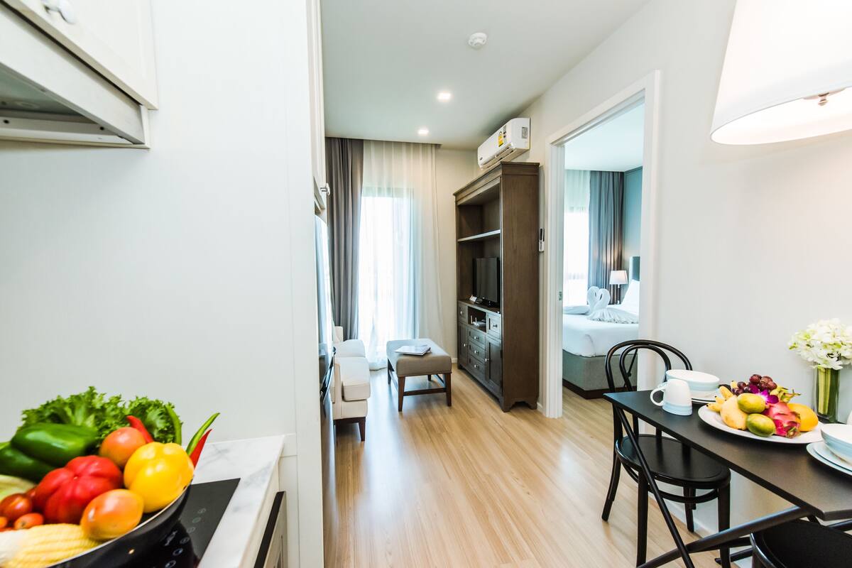 Habitación de hotel moderna con zona de comedor, kitchenette y vistas a la ciudad.