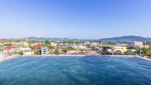 A coastal cityscape with a clear view of the sea and distant mountains. - Dlux Condominium (Chalong)
