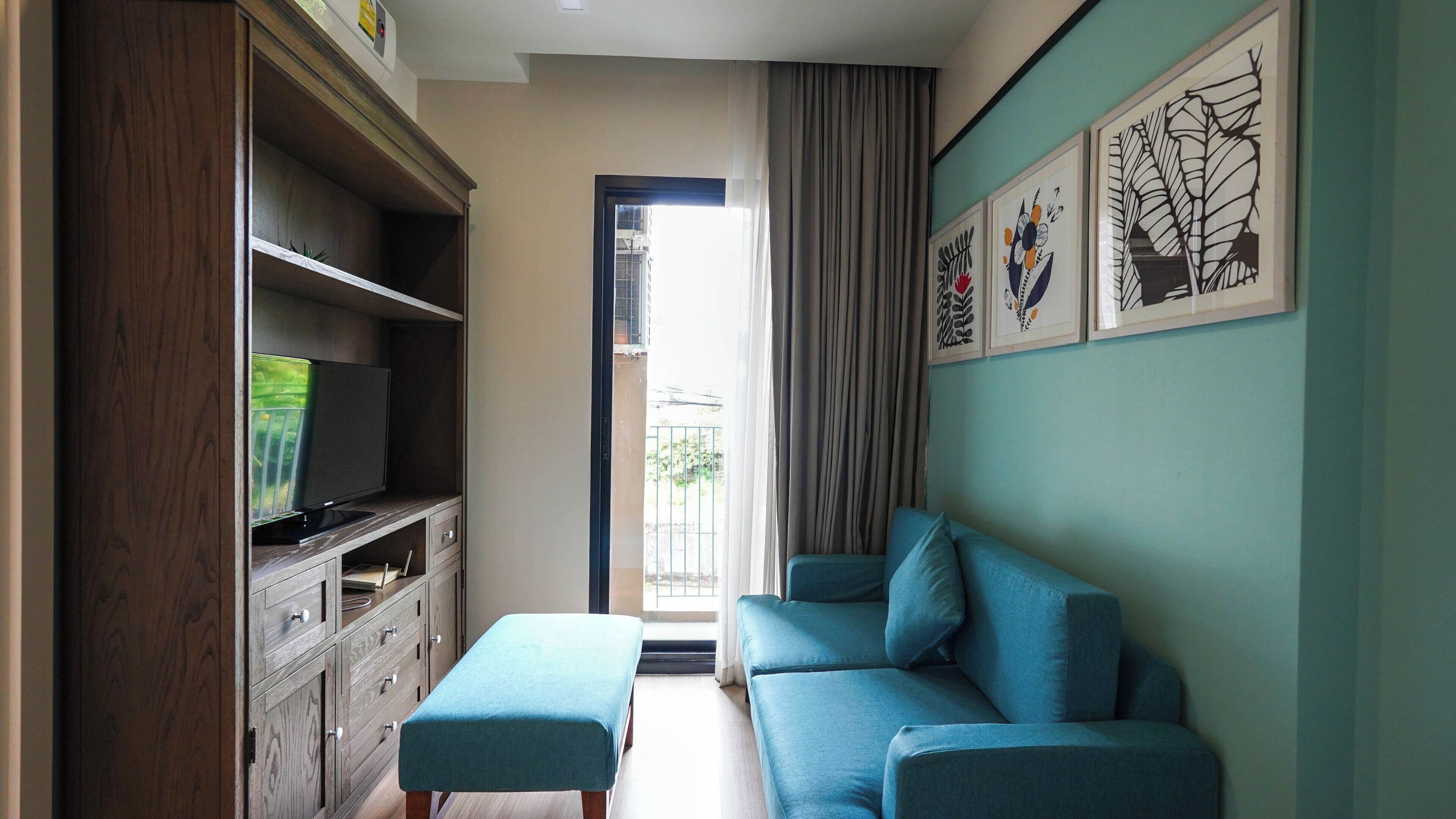A living room with a sofa, a television on a wooden cabinet, and artwork on the wall.
