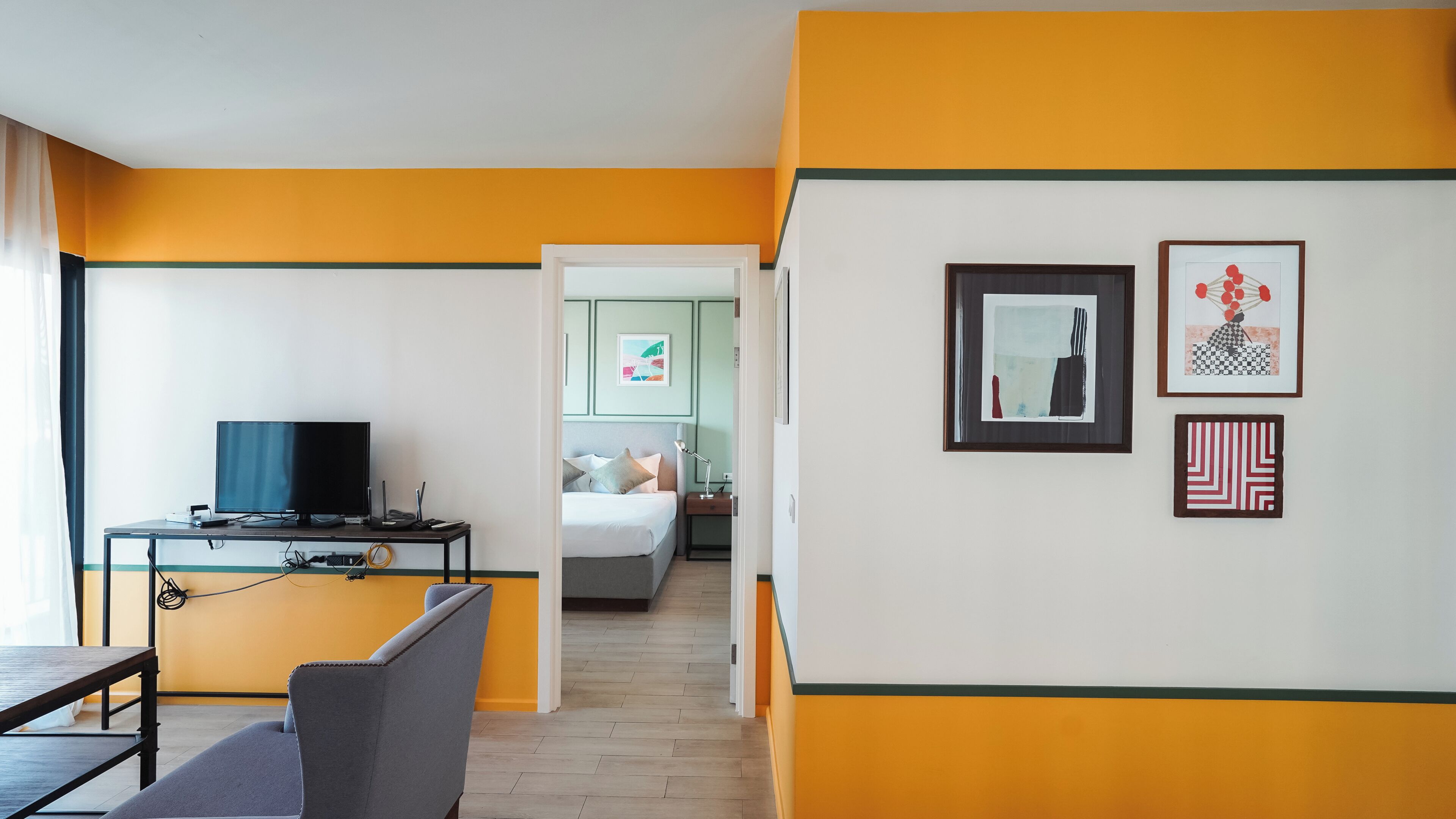 Ein Hotelzimmer mit einem Bett, einem Schreibtisch mit Fernseher und Bildern an der Wand.