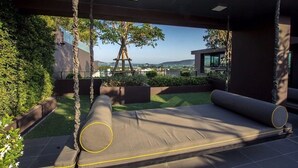 A modern outdoor seating area with a view of the cityscape. - Dlux Condominium (Chalong)