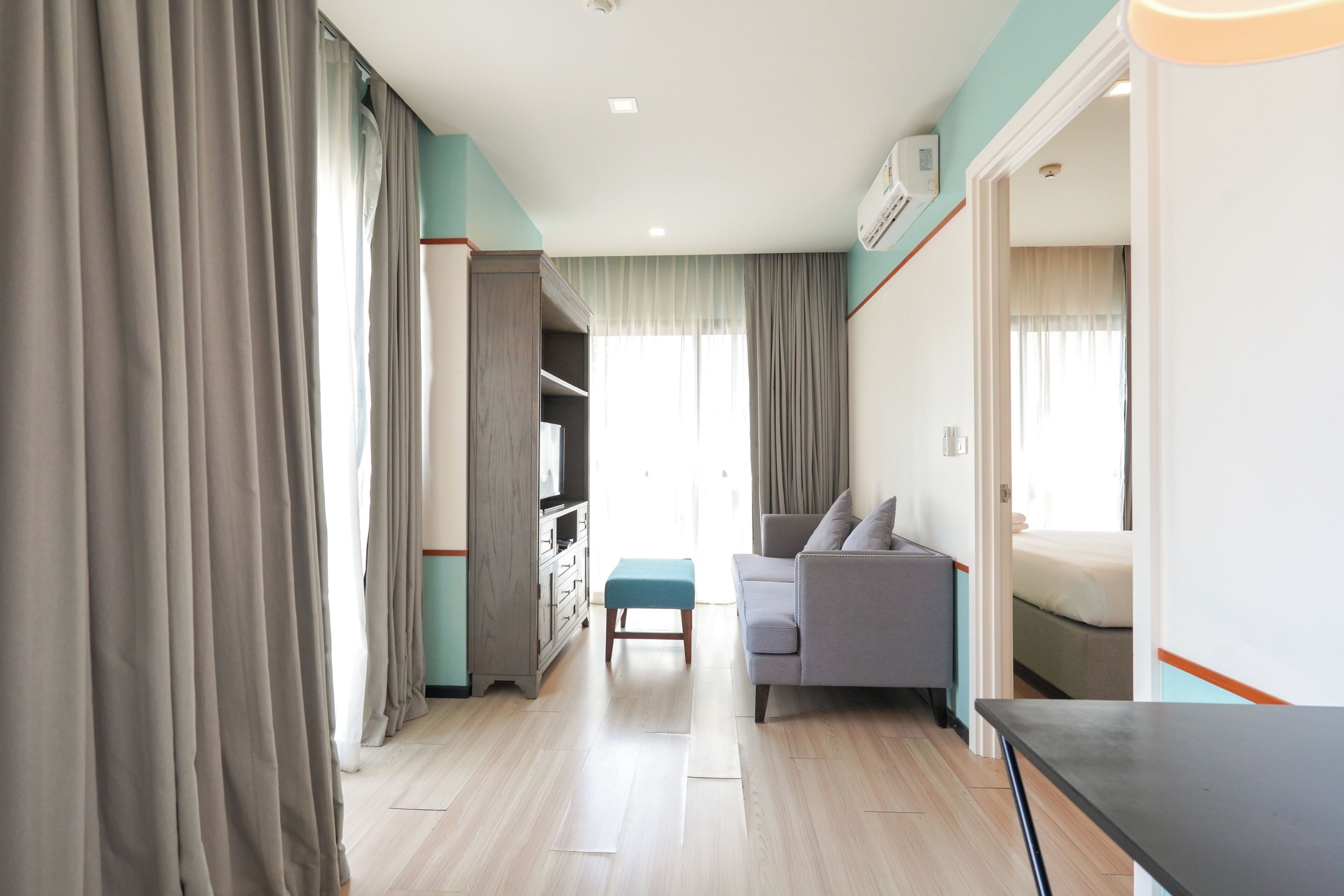 Una habitación de hotel con cama, sofá, una mesita, televisor y armario.