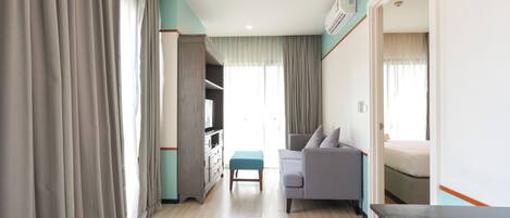 Una habitación de hotel con cama, sofá, una mesita, televisor y armario.