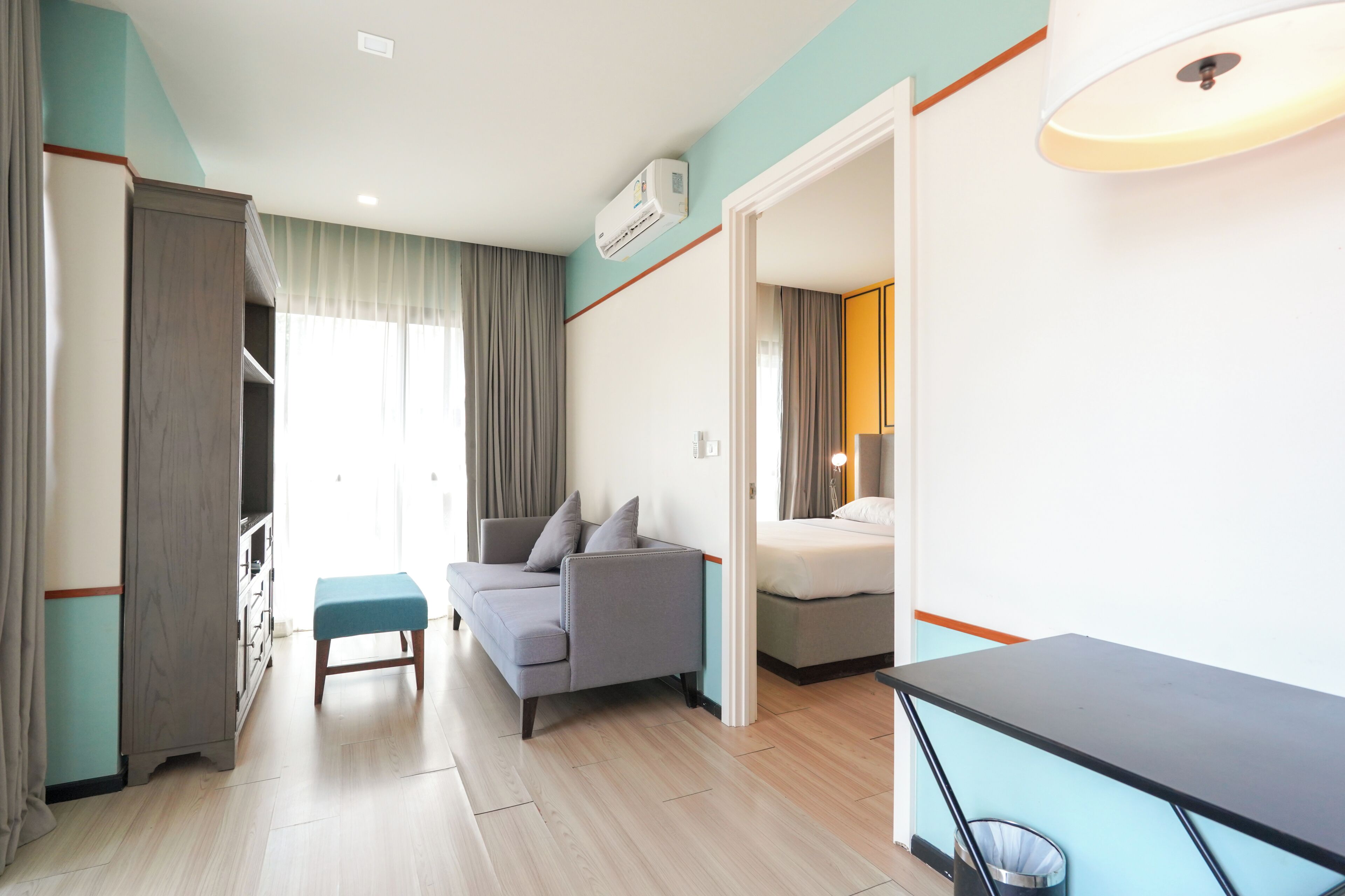 A hotel room with a sofa, a bed, a desk, and a trash bin.